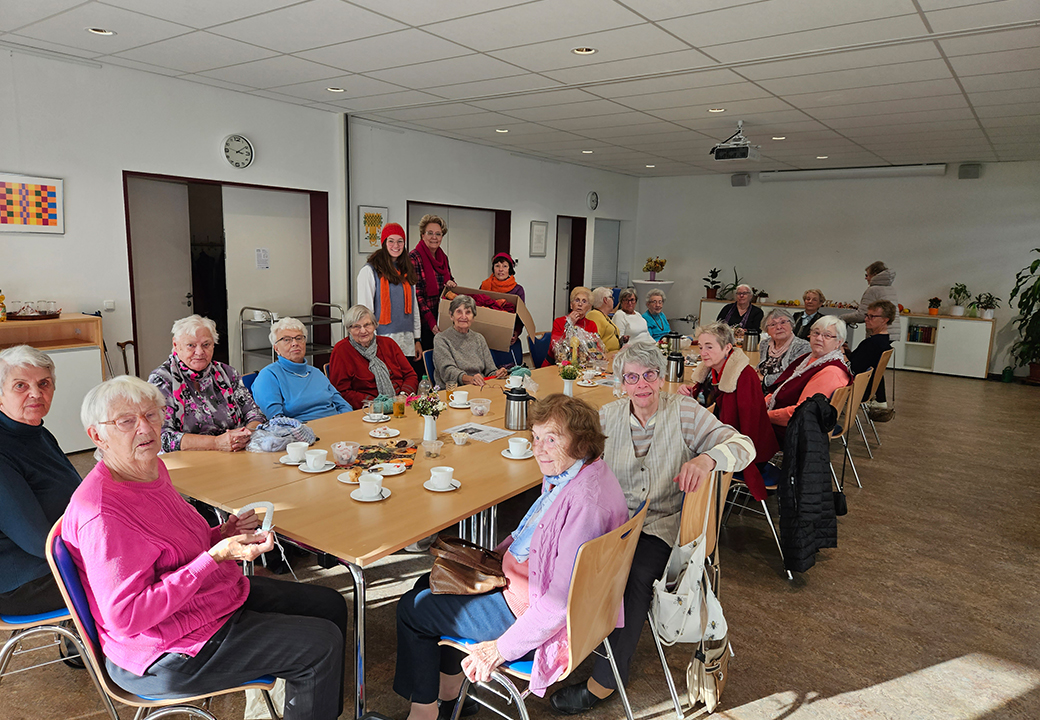 Eine Gruppe älterer Menschen bei einem Treffen in einem Gemeinschaftsraum.