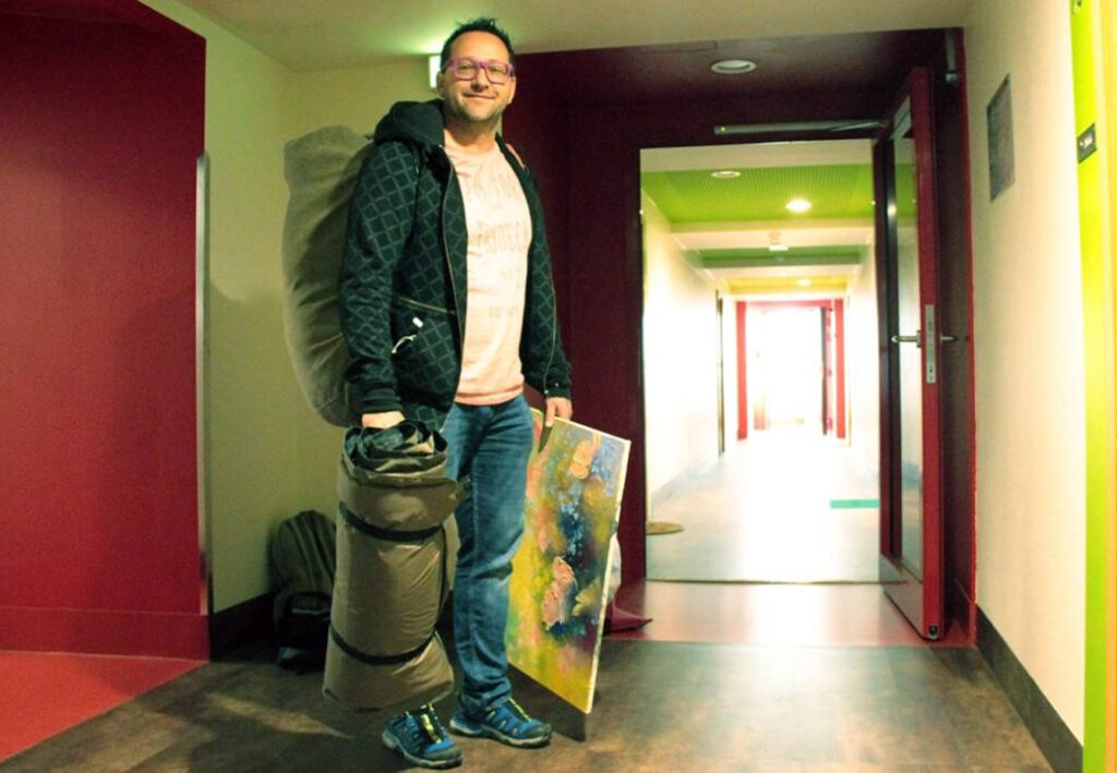 Person mit Schlafsack und Gemälde in einem Flur
