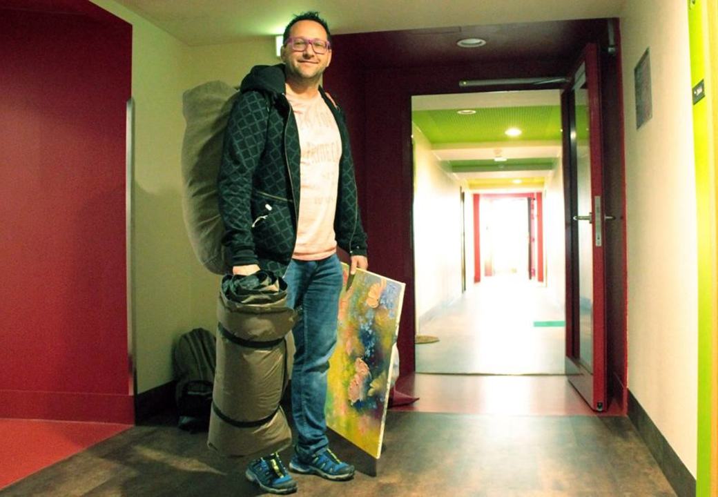 Person mit Schlafsack und Gemälde in einem Flur