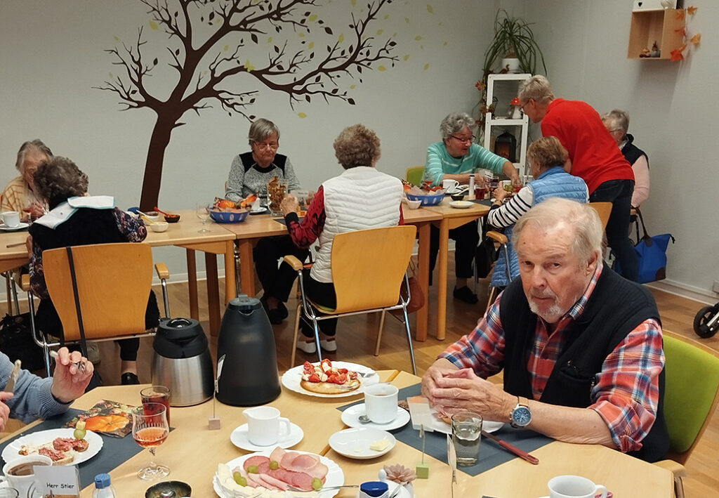 Menschen in einem Gemeinschaftsraum beim Essen.