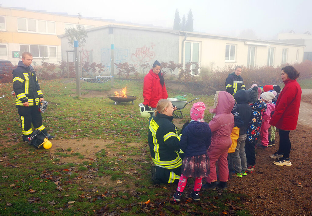 Gruppe von Kindern mit Feuerwehrleuten im Freien