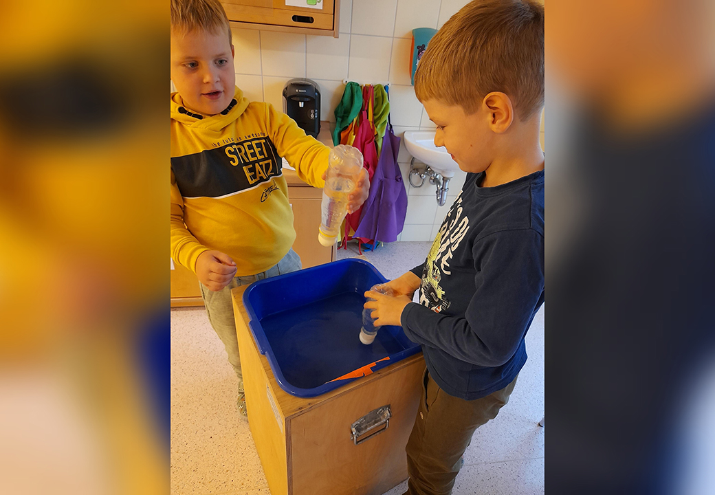 Zwei Kinder führen ein Experiment mit Flaschen durch