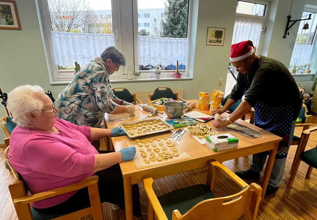 Drei Personen backen Kekse in einer K&uuml;che.