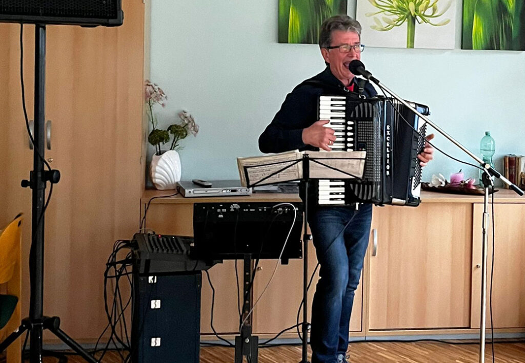 Ein Mann spielt Akkordeon und singt in ein Mikrofon.