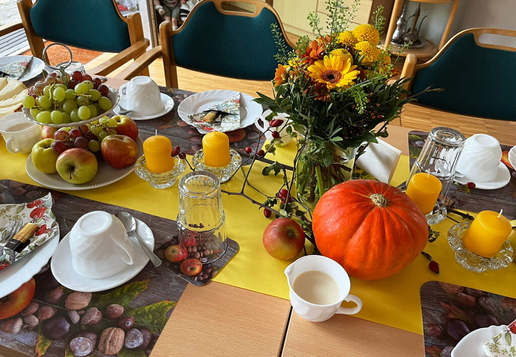 Festlich gedeckter Tisch mit herbstlicher Dekoration, Kerzen und Fr&uuml;chten.