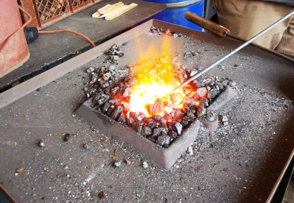 Gl&uuml;hende Kohle in einem Schmiedefeuer mit einer Metallstange.