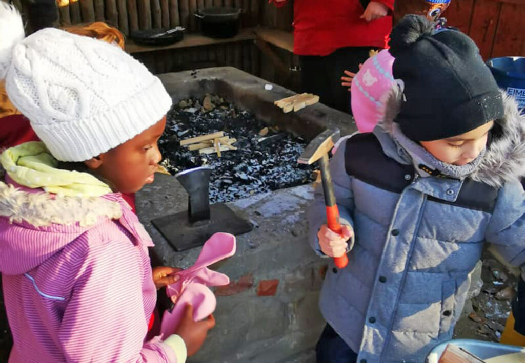 Kinder beim Spielen mit einem Hammer drau&szlig;en im Winter