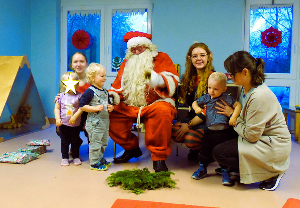 Menschen sitzen mit Weihnachtsmann in einem Raum zusammen