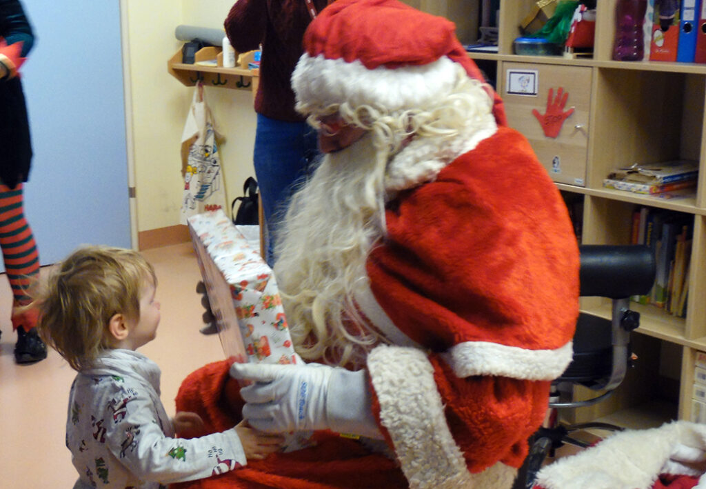 Kind erh&auml;lt ein Geschenk von einer Person im Weihnachtsmannkost&uuml;m