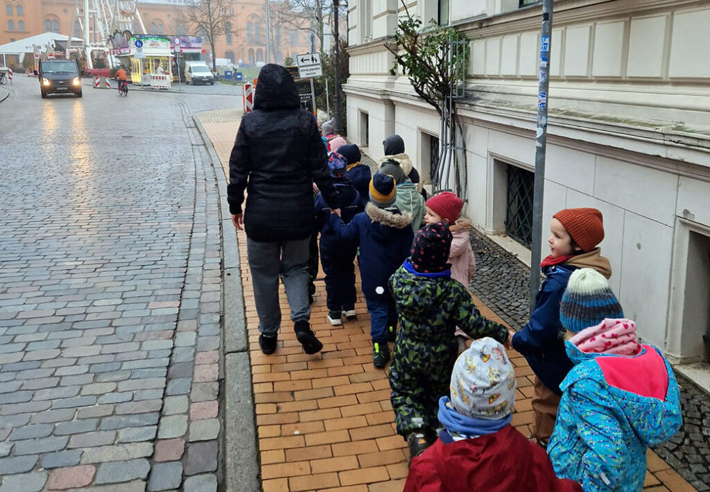 Eine Gruppe von Kindern, die auf einem Gehweg hinter einem Erwachsenen gehen
