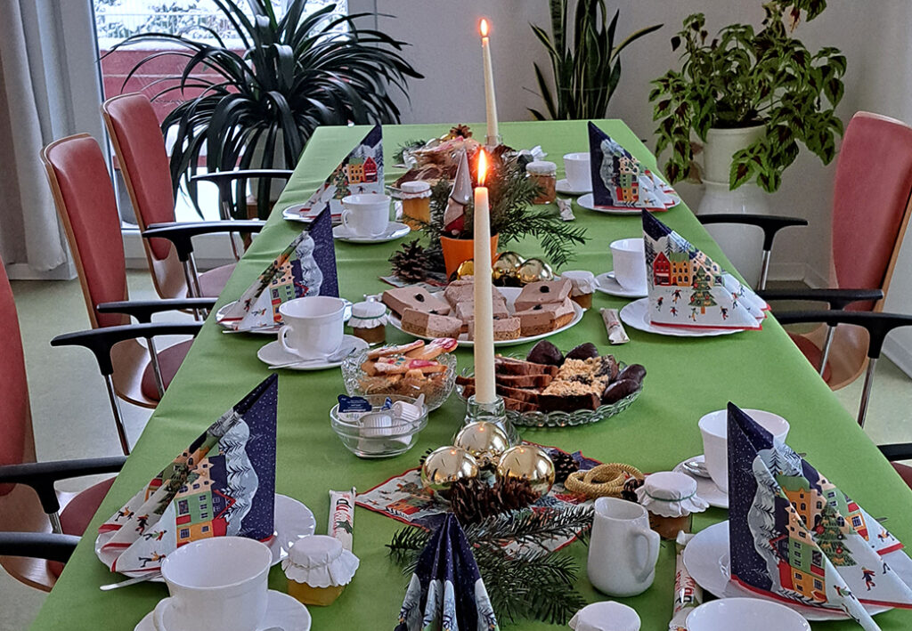 Ein weihnachtlich gedeckter Tisch mit Kerzen, Geb&auml;ck und festlicher Dekoration.