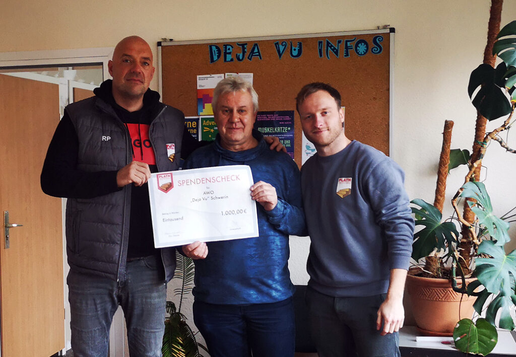 Drei Männer halten einen Spendenscheck.