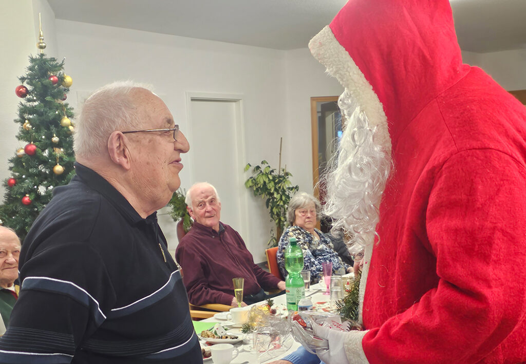 Eine Weihnachtsfeier mit einem Weihnachtsmann und &auml;lteren Menschen.