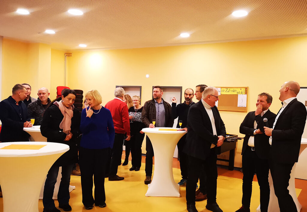 Menschen bei einer Veranstaltung in einem Raum mit Stehtischen