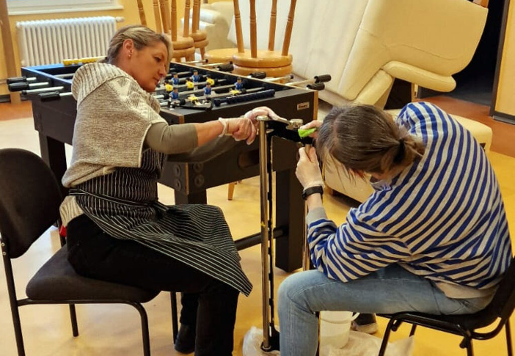 Zwei Personen reparieren einen Tischkicker