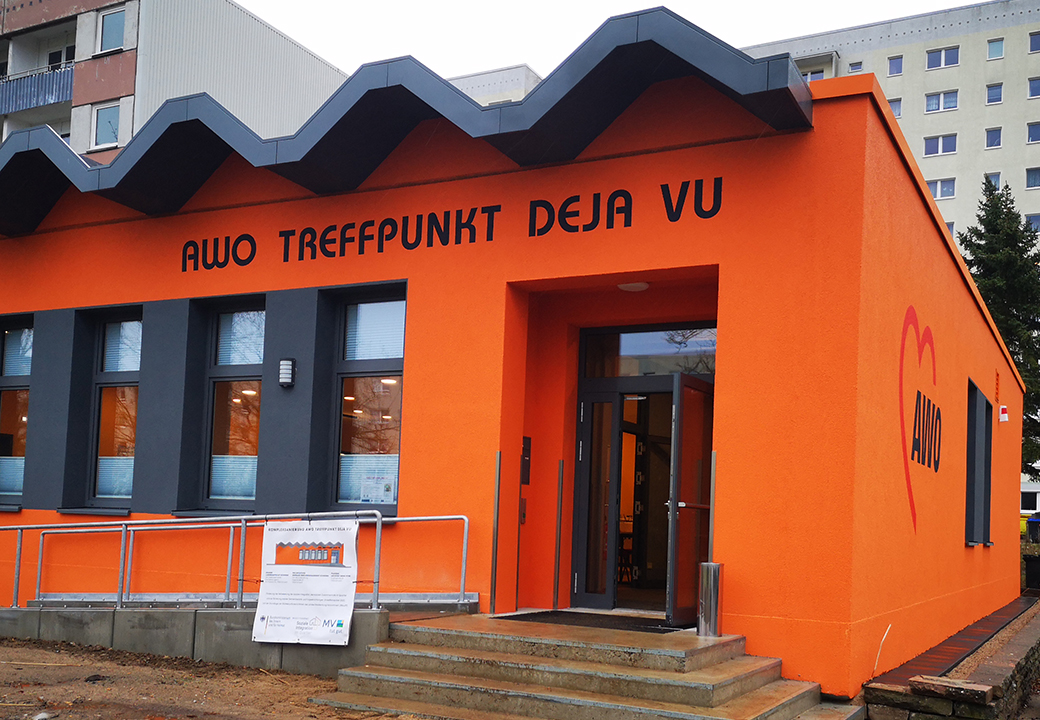 Außenansicht eines orangefarbenen Gebäudes mit der Aufschrift 'AWO Treffpunkt Deja Vu'.