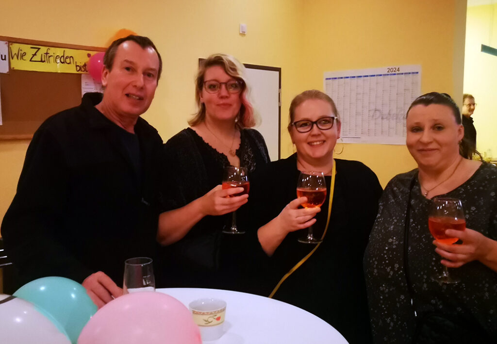 Vier Personen bei einer Feier mit Getr&auml;nken in der Hand.