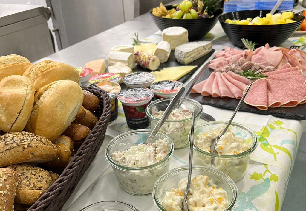 Ein reichhaltiges Fr&uuml;hst&uuml;cksbuffet mit Brot, Aufschnitt, K&auml;se, Aufstrichen und frischem Obst.