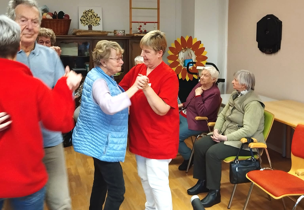 Ältere Menschen tanzen und sitzen in einem Raum