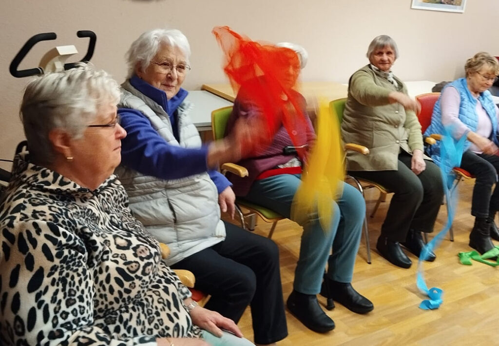 Senioren beim Sitztanz mit farbigen T&uuml;chern.