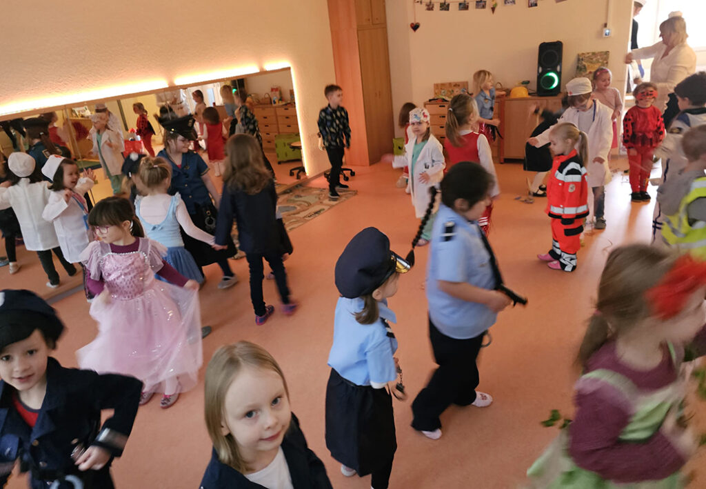 Kinder in Kost&uuml;men tanzen in einem Raum mit Spiegel.