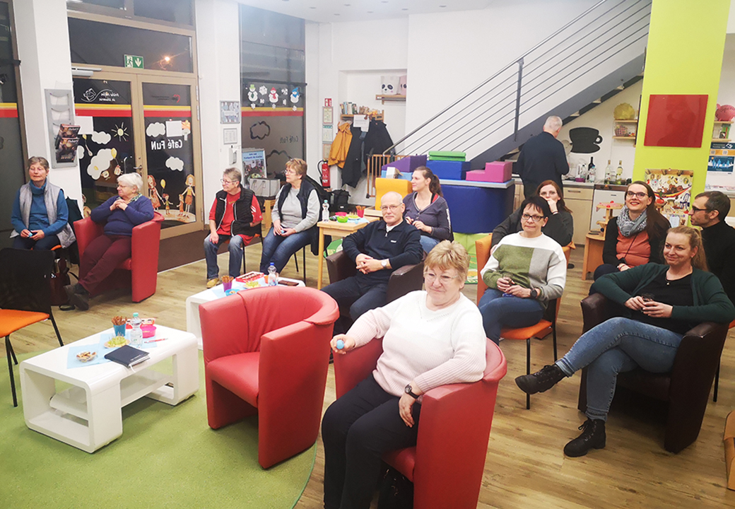 Gruppe von Menschen sitzt in einem Raum mit gemütlicher Atmosphäre