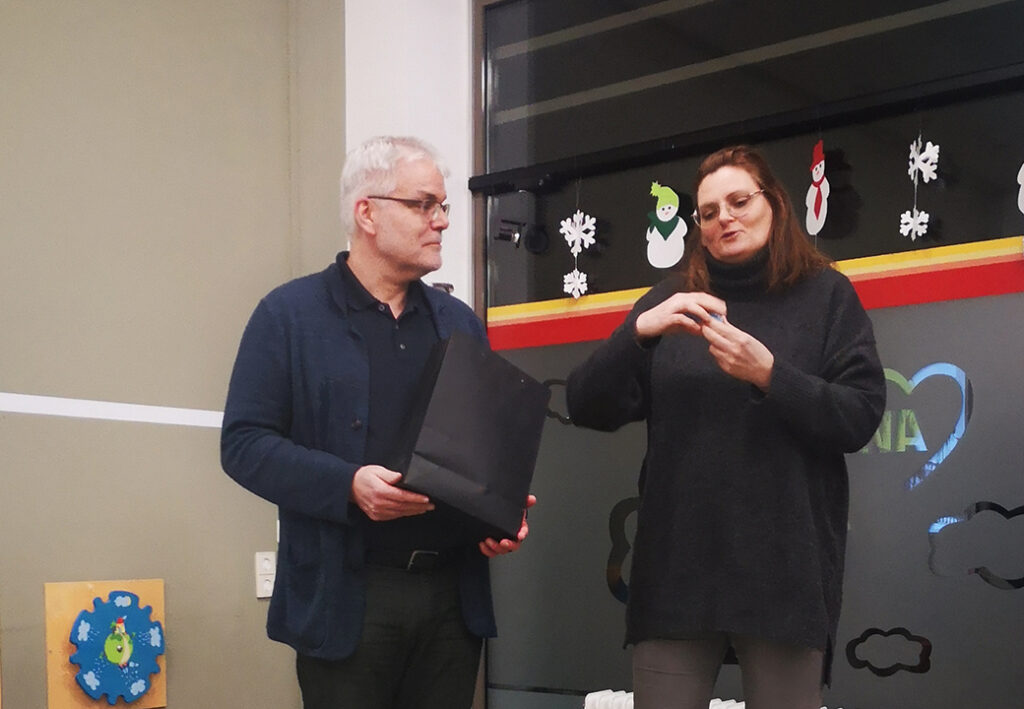 Zwei Personen stehen nebeneinander in einem Raum mit winterlichen Dekorationen.