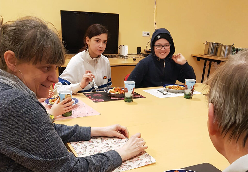 Eine Gruppe von Menschen sitzt um einen Tisch und genie&szlig;t eine Mahlzeit.