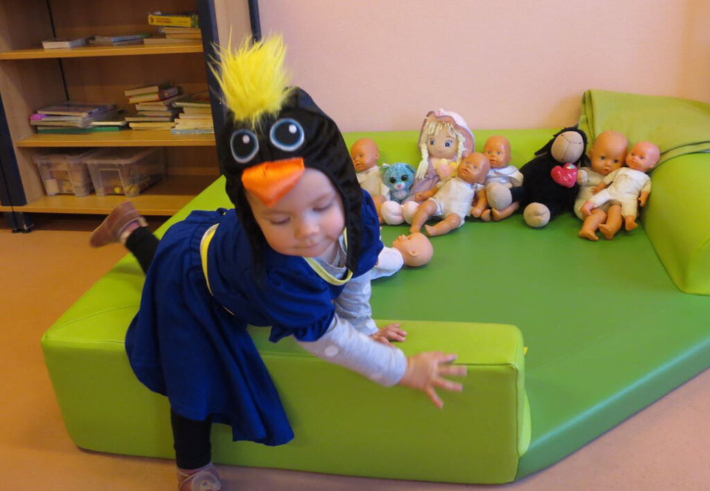 Kleinkind in Vogelverkleidung auf gr&uuml;nem Sofa