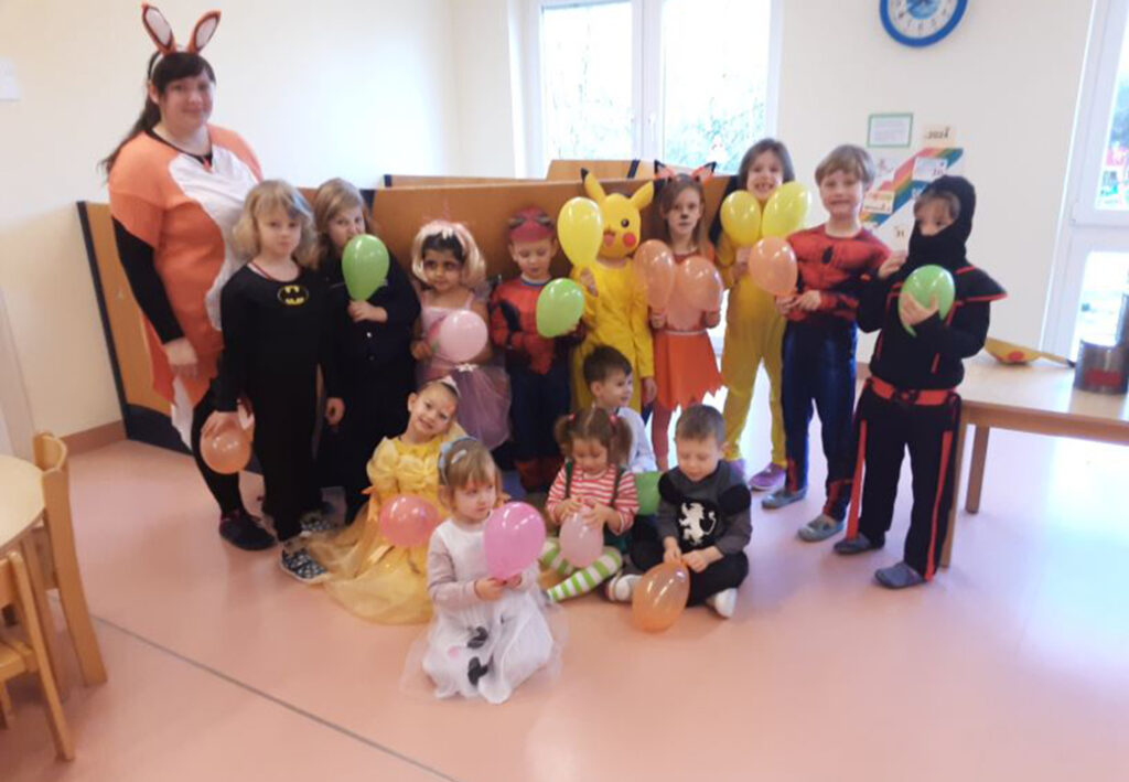 Eine Gruppe von Kindern in Kost&uuml;men mit Luftballons in einem Raum.