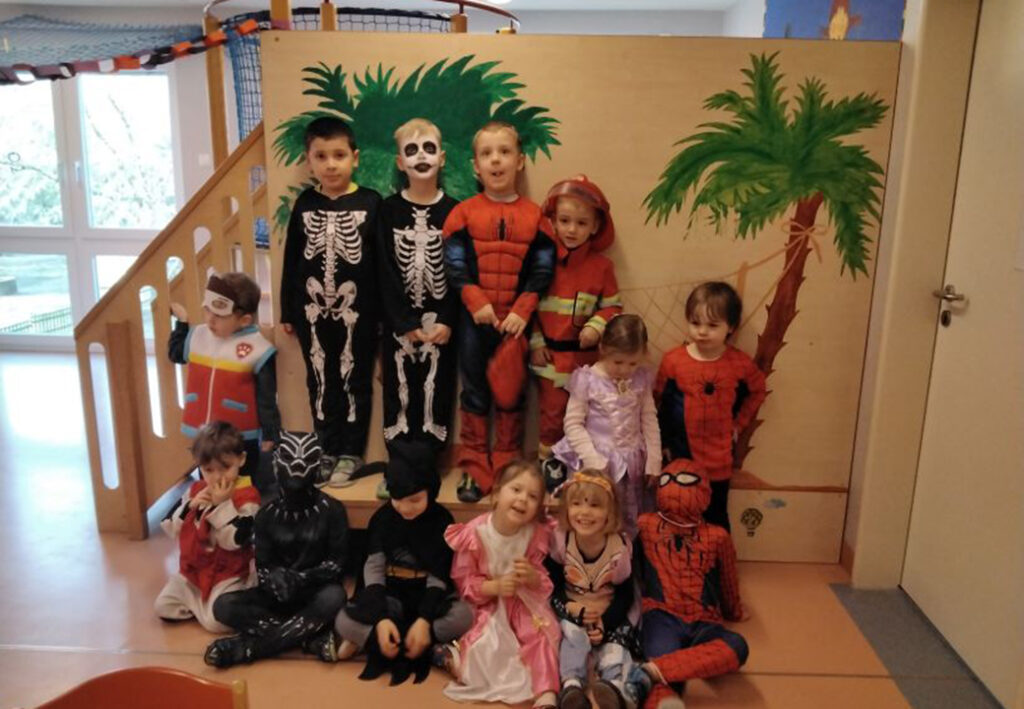 Kinder in Kost&uuml;men vor einer bemalten Wand in einem Raum