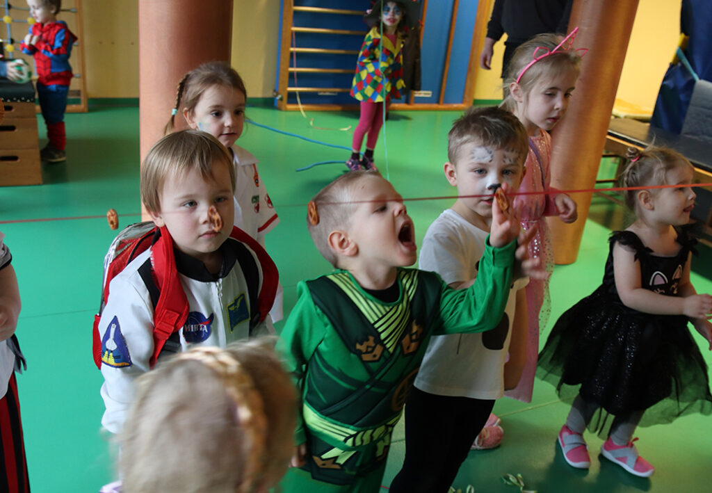 Kinder in Kost&uuml;men bei einem Spiel mit Keksen an einer Schnur