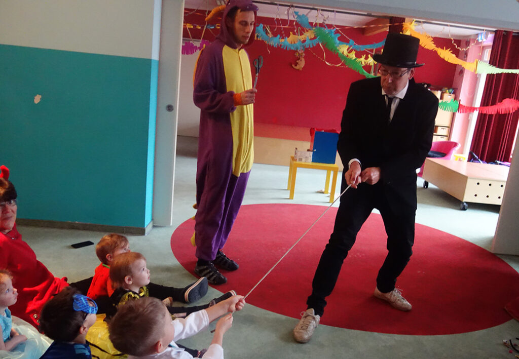 Kinder spielen mit einem als Zauberer verkleideten Mann