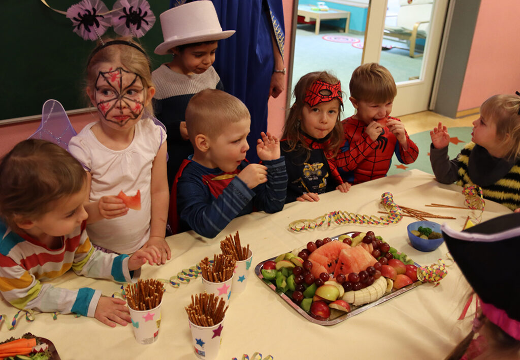 Kinder in Kost&uuml;men bei einer Feier am Tisch mit Snacks und Dekoration