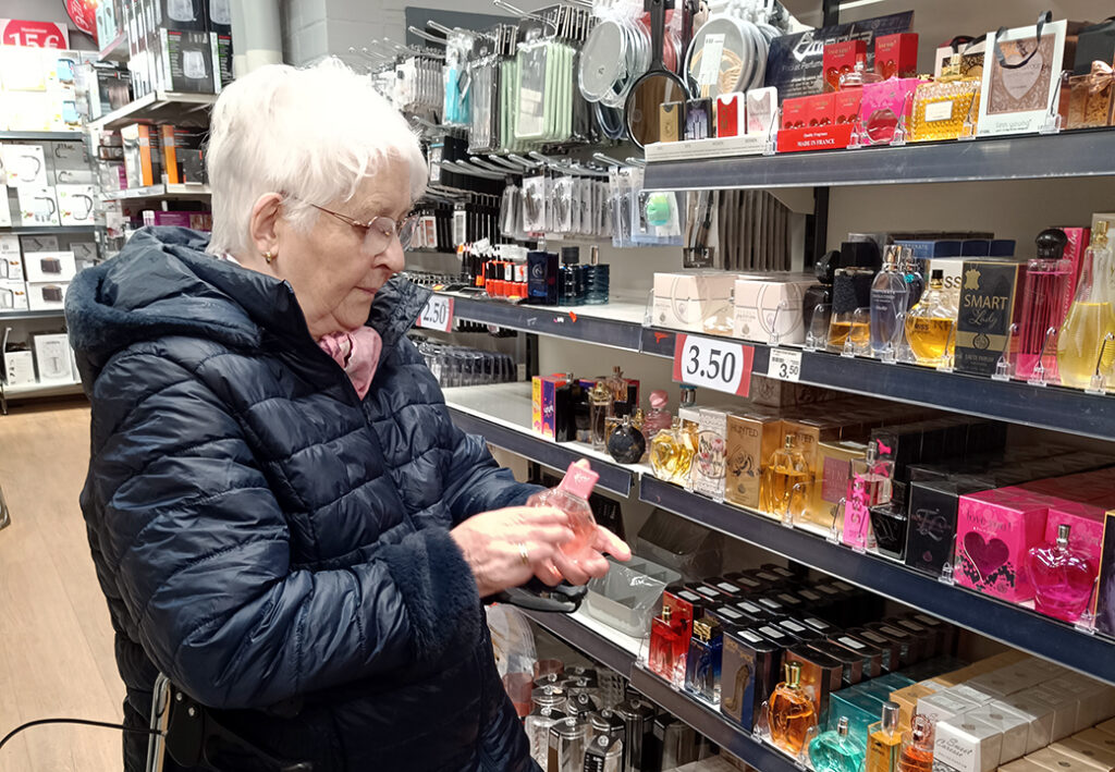 &Auml;ltere Frau betrachtet Parf&uuml;mflasche im Gesch&auml;ft