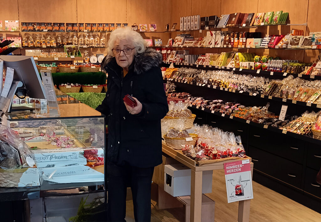 Eine &auml;ltere Frau steht in einem Gesch&auml;ft mit S&uuml;&szlig;waren.