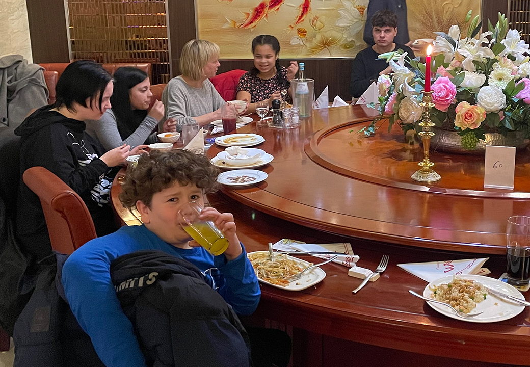 Eine Gruppe von Menschen sitzt an einem großen runden Esstisch in einem Restaurant.