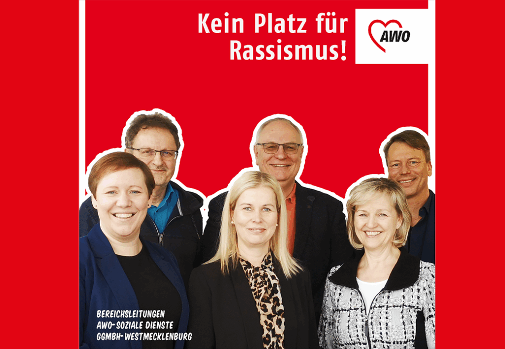 Gruppe von Menschen vor rotem Hintergrund mit der Botschaft 'Kein Platz für Rassismus!'