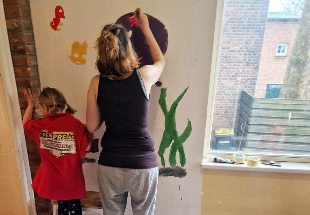 Zwei Personen malen an einer Wand.