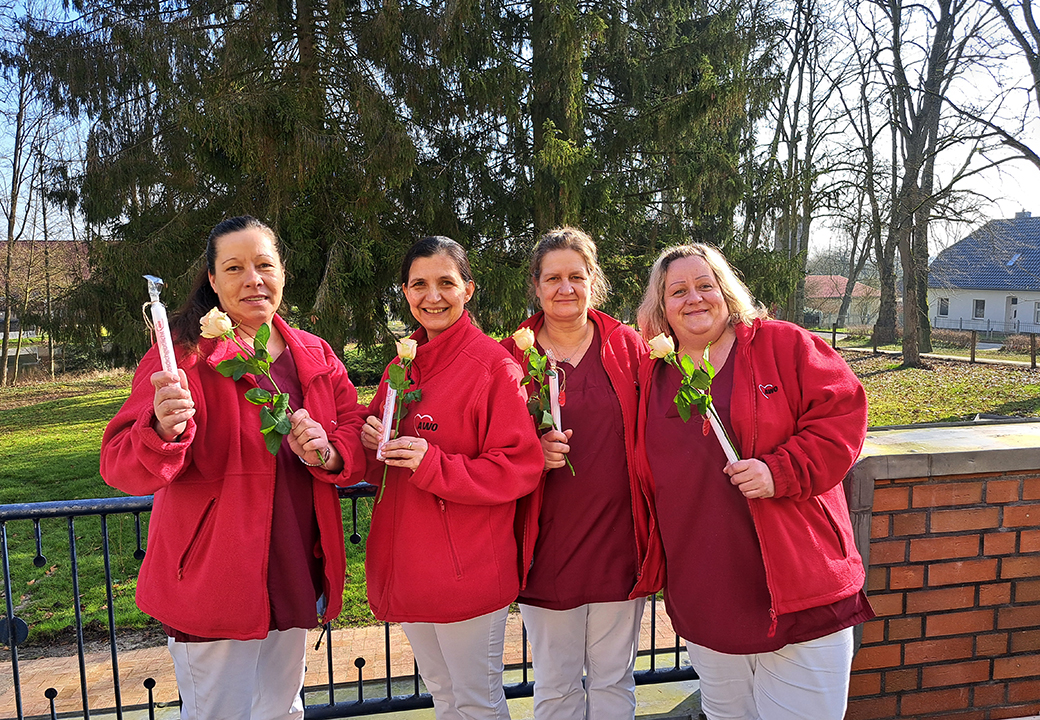 Vier Frauen in roten AWO-Jacken halten Rosen in den Händen