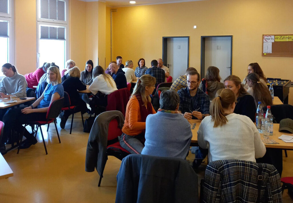 Menschen in einem Seminarraum, diskutierend in Gruppen an Tischen sitzend.