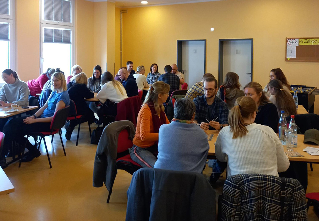Menschen in einem Seminarraum, diskutierend in Gruppen an Tischen sitzend.
