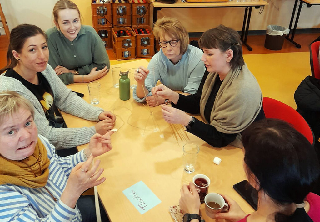 Gruppe von Menschen bei einem Teambuilding-Workshop am Tisch.
