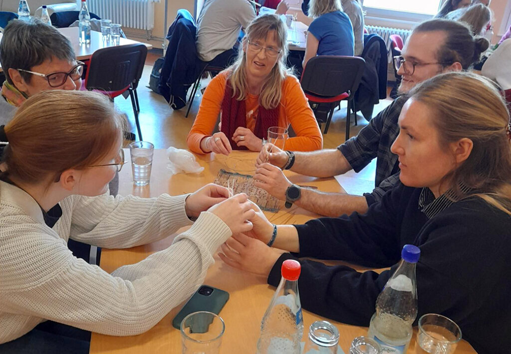 Gruppe von Menschen bei einem Tisch, die an einem Projekt arbeiten