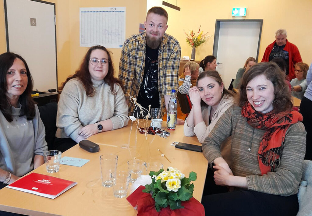 Gruppe von Menschen an einem Tisch bei einem Treffen.