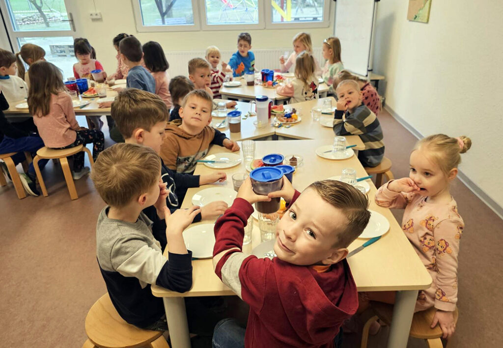 Gruppe von Kindern bei einem gemeinsamen Essen in einem hellen Raum