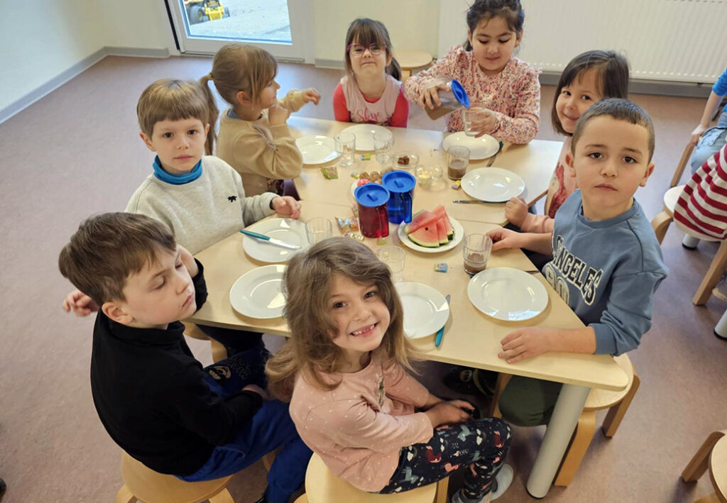 Kinder sitzen an einem Tisch beim Essen
