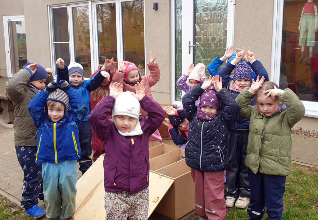Eine Gruppe von Kindern spielt drau&szlig;en vor einem Geb&auml;ude.