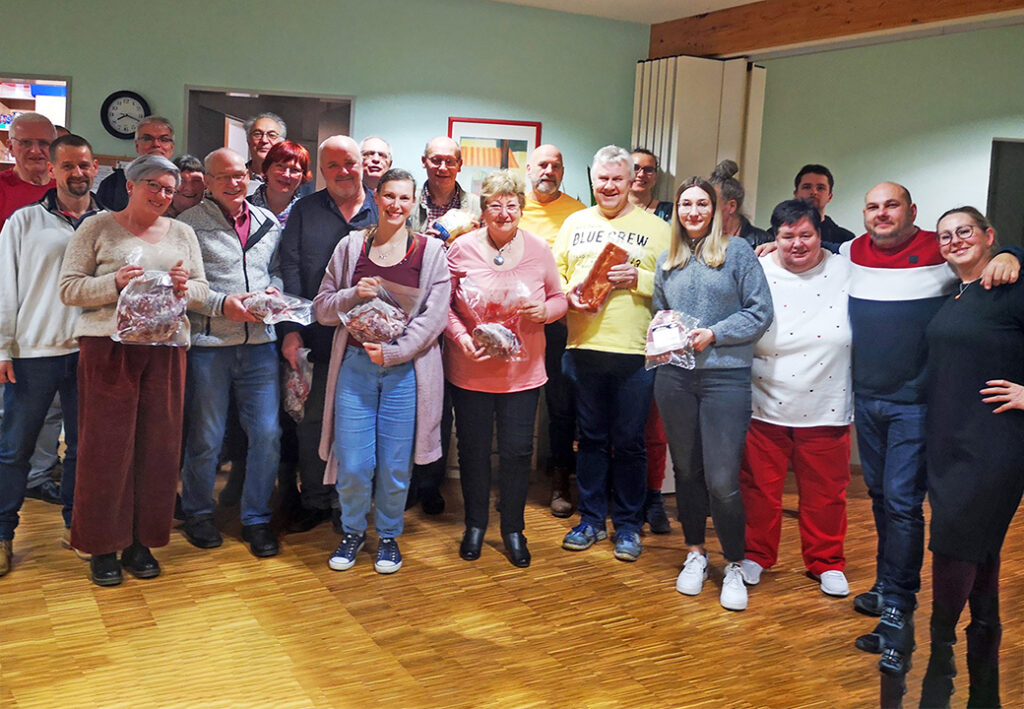 Gruppe von Menschen in einem Raum, die alle l&auml;cheln und Geschenke halten.