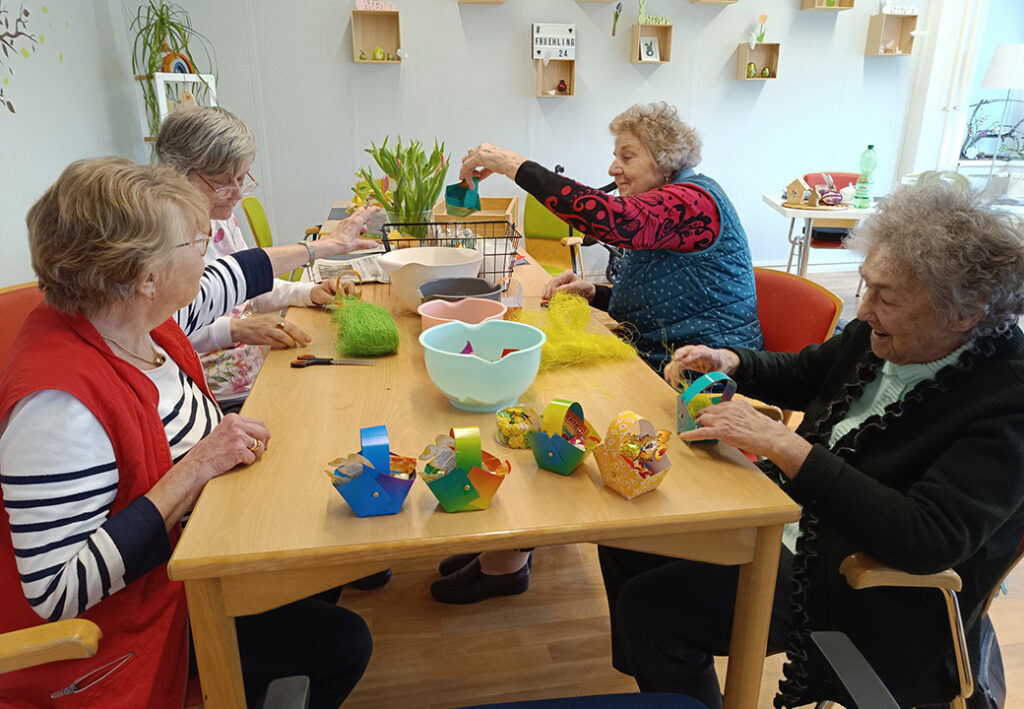 &Auml;ltere Frauen sitzen um einen Tisch und basteln.